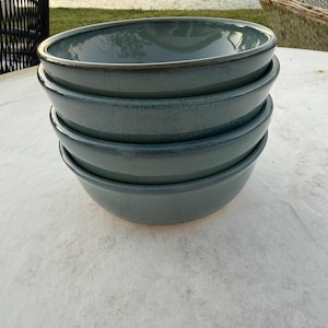 May include: A set of three ceramic mugs with a speckled, matte finish. The mugs are in shades of cream, light grey, and dark grey. Each mug has a simple, minimalist design, ideal for coffee or tea.