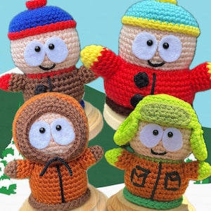 May include: Four crocheted dolls representing cartoon characters. One wears a blue hat with a red pom-pom and brown jacket, one a red jacket with a blue and yellow hat, one an orange hooded parka, and one a green hat with an orange jacket.