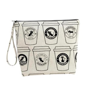 May include: A white canvas zippered pouch with a black and white print of coffee cups and black cats. The print includes the text "CoCoLand" and "Black cats".