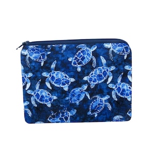 May include: A blue zippered pouch featuring a pattern of white and blue sea turtles. The turtles are scattered across a dark blue background. The pouch has a navy blue zipper and trim.