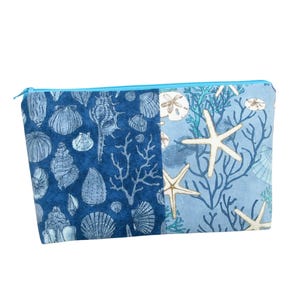 May include: A blue zippered pouch with a seashell and starfish design. The pouch is made of fabric and has a blue zipper.