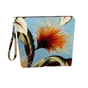 May include: A light blue zippered pouch with a colorful floral pattern. The design features large orange, red, and yellow flowers with green and white leaves. A wrist strap is attached to the side with a silver-colored clasp.