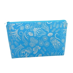May include: A light blue zippered pouch with a silver metallic print of sea life, including jellyfish, seahorses, and seaweed.