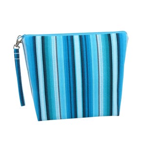 May include: A blue and turquoise striped zippered pouch with a wrist strap. The pouch features a vertical stripe pattern in varying shades of blue and turquoise. The zipper and wrist strap are a solid light blue color.