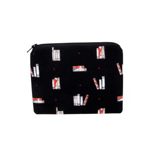 May include: Black zippered pouch with a repeating pattern of white and red book illustrations. The books are arranged in stacks and rows across the surface of the pouch. The zipper is black.
