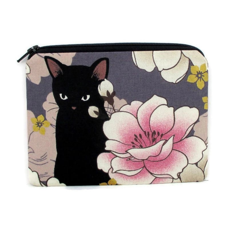 May include: A black cat with a pink flower and other floral designs on a gray background. The cat is looking at the viewer. The design is on a zippered pouch.