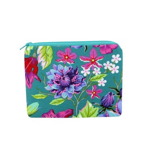 May include: A square teal zippered pouch with a vibrant floral pattern. The design features large purple and blue flowers, smaller pink blossoms, and green leaves. The zipper is a bright turquoise color.