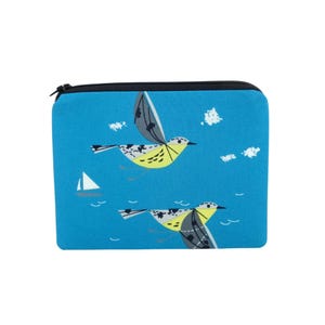May include: A blue zippered pouch featuring a whimsical design of yellow and gray birds in flight, with white clouds and a sailboat. The pouch has a black zipper and a solid blue background.