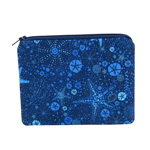 May include: A blue zippered pouch with a repeating pattern of starfish, sand dollars, and bubbles. The pouch is made of fabric and has a zipper closure.