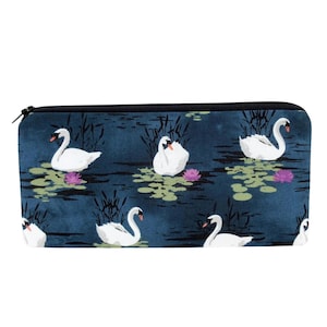 May include: A blue fabric pencil case with a white swan pattern. The swans are swimming in a pond with lily pads and reeds.