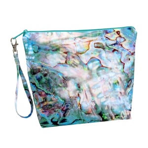 May include: A zippered pouch with a wrist strap, featuring a vibrant, iridescent design in shades of blue, green, and white. The pouch has a teal zipper and a silver-colored clasp. The overall design resembles the surface of an abalone shell.