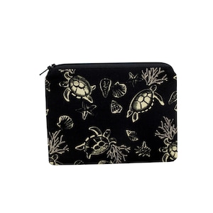 May include: Black zippered pouch with a repeating pattern of sea turtles, starfish, and seashells in a cream color. The pouch is rectangular and has a black zipper closure.