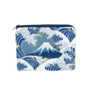 May include: A rectangular zippered pouch featuring a Japanese wave pattern with Mount Fuji in the center. The design includes shades of blue, white, and gold. The pouch has a navy blue zipper and trim.