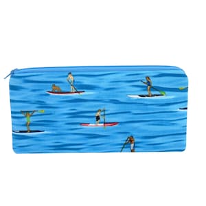 May include: A blue zippered pouch with a repeating pattern of people paddleboarding on a blue ocean.