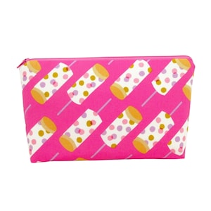 May include: A pink zippered pouch with a repeating pattern of colorful polka dot cylinders. The pouch is made of fabric and has a zipper closure.