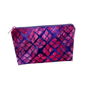 May include: A rectangular cosmetic bag with a vibrant pattern of pink and purple diamond shapes on a dark blue background. The bag has a pink zipper and a matching pull.