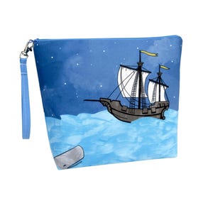 May include: Blue zippered pouch featuring a nautical illustration of a ship sailing on a wavy sea under a starry night sky. The design includes a whale and yellow flags. The pouch has a blue wrist strap.