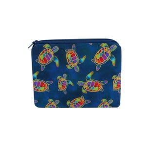 May include: A rectangular zippered pouch featuring a dark blue background with a repeating pattern of sea turtles. Each turtle has a vibrant, multi-colored shell with segments in shades of red, orange, yellow, green, and purple, outlined in gold.