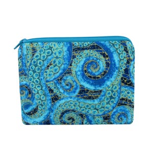 May include: A rectangular zippered pouch featuring a blue and gold octopus tentacle design. The pouch has a teal zipper and a matching teal border. The fabric has a dark blue background with swirling tentacles in shades of blue and gold.
