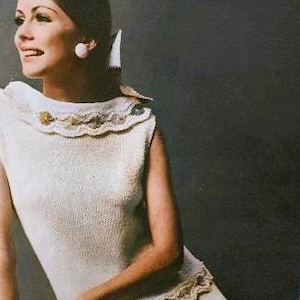May include: A white sleeveless knitted top with a crocheted lace trim around the neckline. The top has a delicate, feminine design and is perfect for a casual summer outfit.