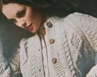 May include: A cream-colored cable knit cardigan with a button closure and a white collared shirt underneath.