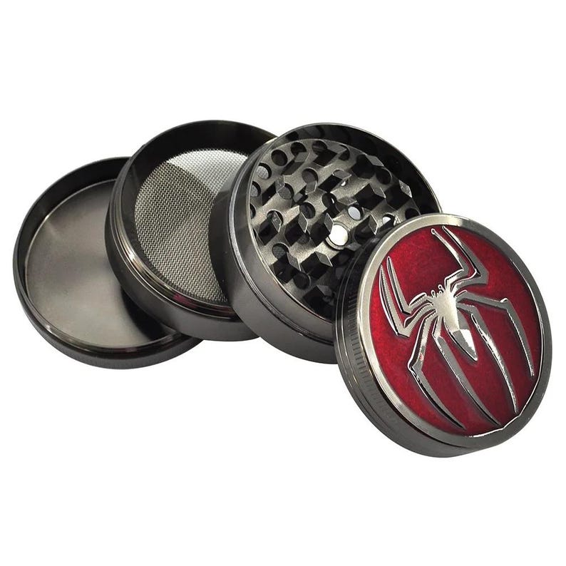 May include: A four-piece, gunmetal-colored herb grinder with a red and silver spider emblem on the lid. The grinder is disassembled, revealing the mesh screen and grinding teeth.