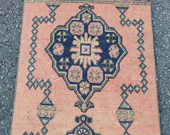 May include: A rectangular, vintage-style rug with a peach background and intricate geometric patterns in navy blue, olive green, and beige. The rug features a central medallion design and border details.