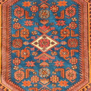 May include: A detailed, rectangular rug with a central blue field. The rug features a complex geometric pattern in shades of orange, red, and cream. The border is a dark brown with a repeating design. The rug's design is symmetrical.