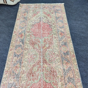 Könnte beinhalten: Rechteckiger Vintage-Teppich mit einem zentralen roten Medaillon-Design, umgeben von aufwendigen floralen und geometrischen Mustern in Blau-, Grün- und Beigetönen. Der Teppich hat ein abgenutztes, gealtertes Aussehen, was auf ein antikes Stück hindeutet.