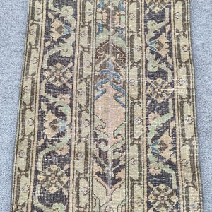 May include: A rectangular, vintage-style rug with a vertical striped pattern. The rug features a central design with a light brown background and floral motifs in shades of blue, green, and brown. The borders are dark brown.