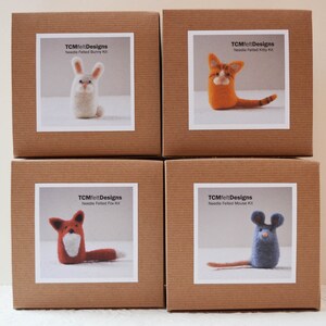 Pode incluir: Quatro caixas de cart&atilde;o castanhas, cada uma com uma etiqueta branca com um kit de animais de feltro com agulha. Os kits incluem um coelho, um gato, uma raposa e um rato. Os r&oacute;tulos dizem "TCMfeltDesigns Needle Felted [Animal] Kit."