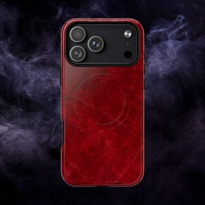 May include: Red phone case with a textured, marble-like appearance. The case has a black camera module with three lenses and a circular design on the back. The case is designed to fit a smartphone.
