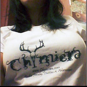 May include: A white t-shirt with a black graphic of a skull with antlers and the word "Chymiera" in a stylized font. The text "www.Chymiera.com, Beads, Jewelry, Oddities & Adornments" is printed below the graphic.