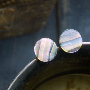 May include: Two round iridescent earrings with a white, blue, and brown striped pattern.