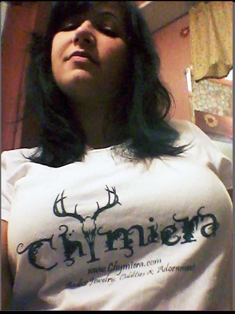 May include: A white t-shirt with a black graphic of a skull with antlers and the word "Chymiera" in a stylized font. The text "www.Chymiera.com, Beads, Jewelry, Oddities & Adornments" is printed below the graphic.