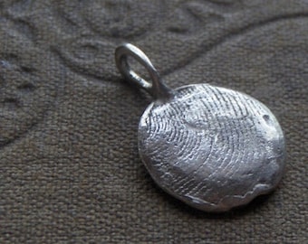May include: A silver pendant with a textured, circular design. The pendant has a loop at the top for attaching to a chain.