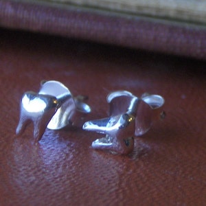 Pode incluir: Um par de brincos de prata em forma de dente. Os brincos são pequenos e delicados, e são perfeitos para adicionar um toque de fantasia a qualquer roupa.