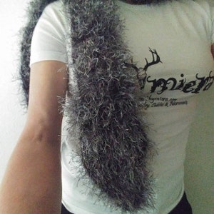 May include: A white t-shirt with a black deer head and the word "mier" printed on the front. The shirt is worn with a gray fluffy scarf.