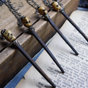 May include: Four necklaces with rusty nail pendants and small bone skull charms. The necklaces are displayed on a vintage book with text in a foreign language.