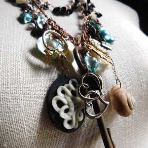 May include: A multi-strand necklace featuring a range of charms, including a key, a heart, a seashell, and assorted beads. The necklace is crafted from copper, silver, and other materials.