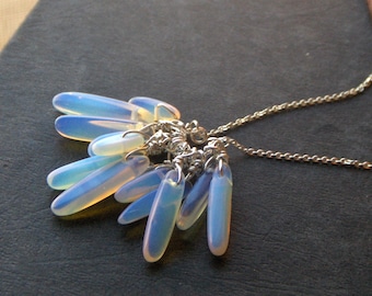 May include: A silver chain necklace with a cluster of iridescent blue and white teardrop-shaped opal stones hanging from it.