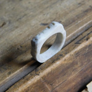 May include: A white bone ring with a smooth, rounded surface. The ring is made from natural bone and has a unique, organic shape.