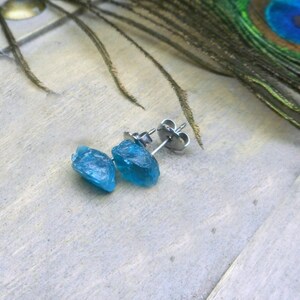 May include: A pair of blue gemstone earrings with silver posts. The gemstones are rough and irregular in shape.