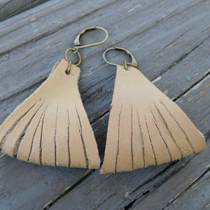 May include: A pair of tan leather fringe earrings with gold-toned hooks.