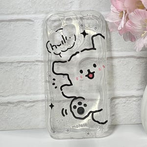 May include: Clear phone case with a cartoon Maltese dog design. The case features a white outline of a dog with pink cheeks, paw prints, and the word "hello" in a speech bubble. The word "maltese" is also visible.
