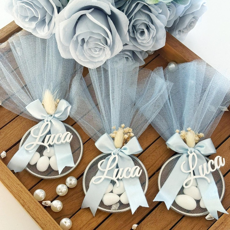 Personalized blue baptism favor with almond candies, custom name ‘Luca’ on acrylic tag, wrapped in soft blue tulle with satin ribbon and dried flowers – elegant handmade bomboniere for baby boy christening or baby shower