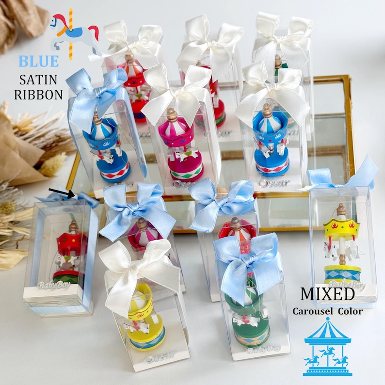 Pink carousel party favors in clear gift boxes with satin ribbons and personalized acrylic names – ideal for baby showers or baptisms. Close-up of pink carousel keepsakes with gold and silver bows, featuring custom names and elegant acrylic details. Colorful carousel favors (red, blue, green, yellow) with festive ribbons, designed as personalized welcome baby or birthday gifts.