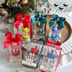 Pink carousel party favors in clear gift boxes with satin ribbons and personalized acrylic names – ideal for baby showers or baptisms. Close-up of pink carousel keepsakes with gold and silver bows, featuring custom names and elegant acrylic details. Colorful carousel favors (red, blue, green, yellow) with festive ribbons, designed as personalized welcome baby or birthday gifts.