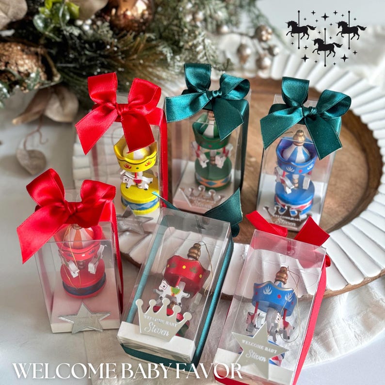 Pink carousel party favors in clear gift boxes with satin ribbons and personalized acrylic names – ideal for baby showers or baptisms. Close-up of pink carousel keepsakes with gold and silver bows, featuring custom names and elegant acrylic details. Colorful carousel favors (red, blue, green, yellow) with festive ribbons, designed as personalized welcome baby or birthday gifts.