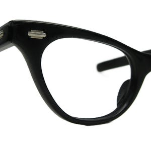 May include: Black cat-eye glasses with a silver accent on the frame.